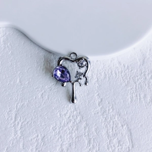 Close-up of liquid metal heart pendant with purple pear-cut gem and white zircons