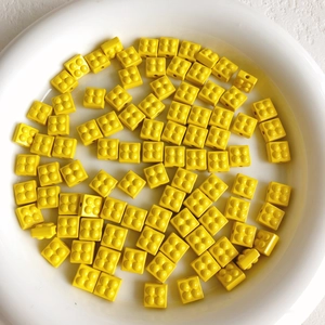 Close-up of bright yellow block beads in a white bowl for DIY jewelry making