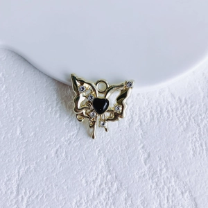 Detail of a gold butterfly pendant with a black heart and sparkling rhinestones