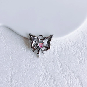 Macro view of silver butterfly pendant with pink heart gemstone and sparkling zircons