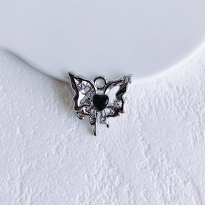 Macro shot of silver butterfly pendant with black heart center and sparkling rhinestones