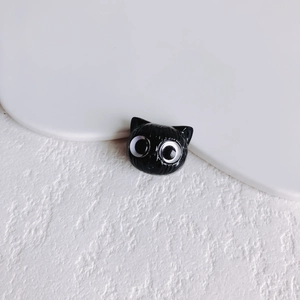 Makro-Ansicht eines glänzend schwarzen Katzenkopf-Anhängers für DIY-Schmuck auf Marmor
