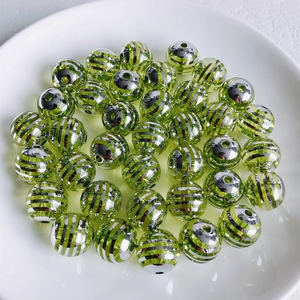Makro-Detail von grün-silber gestreiften Acrylperlen mit Durchgangslöchern für DIY-Schmuck