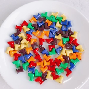 Close-up of colorful macaron-style mini boot charms in a white ceramic dish