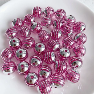 Nahaufnahme von silbernen und rosaroten gestreiften Acrylperlen für DIY-Schmuck