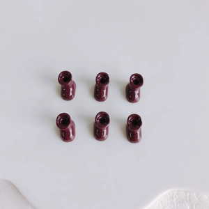 Macro detail of six miniature wine red resin boot charms for DIY jewelry and crafts