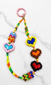 Detalle de cordón de cuentas color dopamina con dijes de corazón y cierre de muelle
