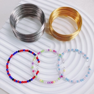 Memory wire coils in gold and silver with colorful beaded bracelets on a white tray