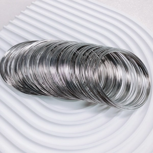 Detail of silver memory steel wire coils for DIY jewelry making on white textured surface