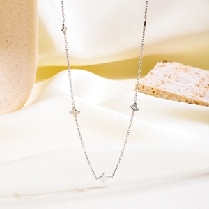 Elegant silver four-leaf clover necklace displayed on aesthetic satin background