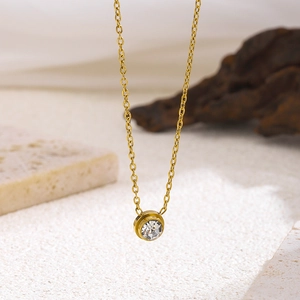 Minimalist gold titanium necklace with single round rhinestone pendant on a white base