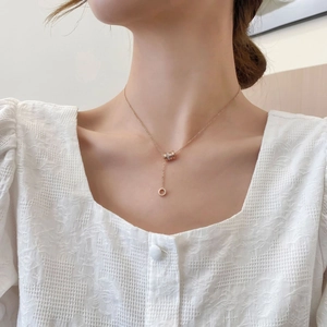 Rose gold 18k roman numeral cylinder necklace with tassel worn on a female model neck