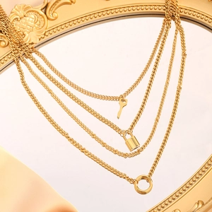 Retro goudkleurige gelaagde ketting met sleutel- en slotvormige hangers op zijden stof