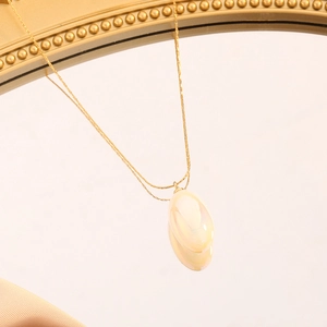 Detail of gold pear-shaped opal pendant necklace on a vintage mirror background