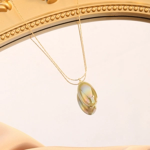 Macro shot of a pear-shaped rainbow pendant on a gold necklace over silk fabric