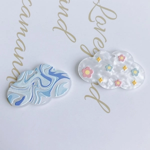 Detail of cloud-shaped acrylic charms with abstract marble patterns and floral prints