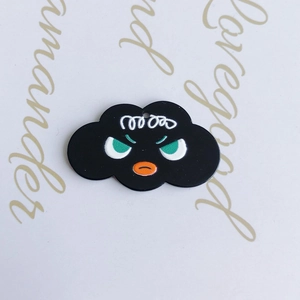 Macro detail of cloud-shaped black pendant with cartoon face for DIY jewelry