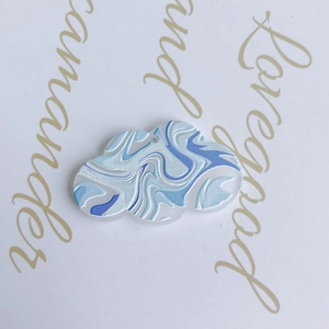 Macro shot of cloud-shaped acrylic charm with blue and white marble pattern for DIY jewelry