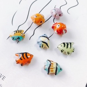 Macro shot of colorful ceramic fish beads with glaze finish and holes for DIY jewelry