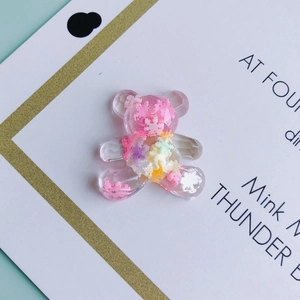 Detail view of a pink resin bear charm filled with colorful snowflake sequins