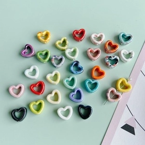 Flat lay of heart-shaped hollow DIY beads in various solid colors and marble patterns