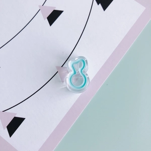 Detail of clear acrylic figure-eight charm with mint green center for DIY hair accessories