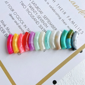 Close-up of translucent curved tube beads with colorful marble texture for DIY jewelry