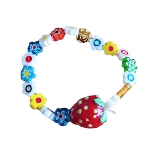 Detailansicht bunter Blumenperlen und eines roten Erdbeeranhängers am süßen DIY-Armband