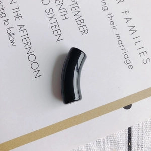 Close-up of a glossy black curved resin tube bead for DIY necklace and bracelet crafting
