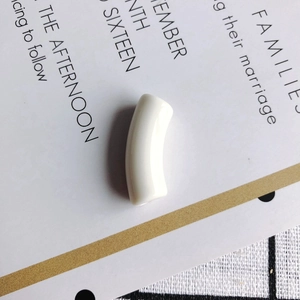 Close-up of a glossy cream white curved tube bead for DIY jewelry making and crafts