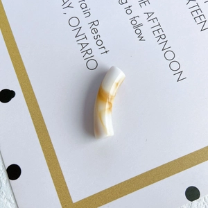 Macro view of a curved translucent acrylic bead with amber marble patterns for DIY jewelry