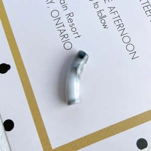 Close-up of a translucent gray-white marble texture curved tube bead for DIY jewelry