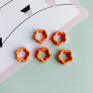 Detalle de cinco cuentas de flores de cerámica naranja con texturas marmoleadas