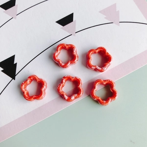 Detalle macro de cuentas de cerámica en forma de flor roja con manchas para joyería DIY