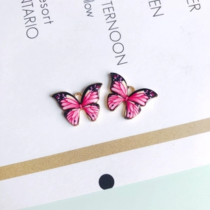Makroaufnahme von zwei rosa-schwarzen Schmetterlingsanhängern mit goldenen Rändern für DIY