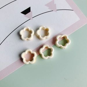 Primer plano de cinco cuentas de flores huecas de cerámica crema para joyería DIY