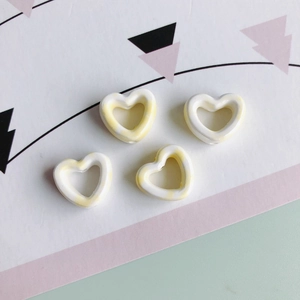 Detail von vier hohlen Herz-Keramikperlen mit gelbem Marmormuster für DIY-Schmuck