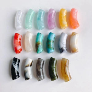 Détail macro de perles tubes courbes en acrylique avec motifs marbrés colorés pour bijoux DIY
