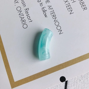 Détail d'une perle tube courbé en acrylique marbré bleu clair pour bijoux DIY