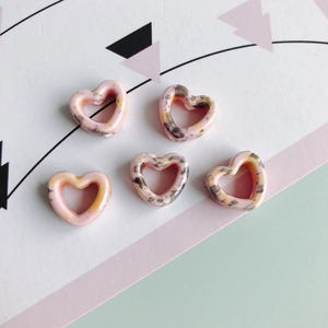Makroansicht von fünf rosa herzförmigen Keramikperlen mit Leopardenmuster für DIY-Schmuck