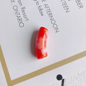 Vue détaillée d'une perle tube courbé en acrylique marbré rouge et blanc pour bijoux