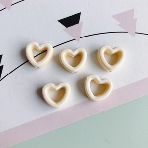 Detailansicht von fünf cremefarbenen Keramikperlen in Herzform für DIY-Schmuck