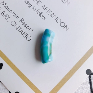 Détail de perles tubulaires courbées en acrylique marbré bleu pour bijoux DIY