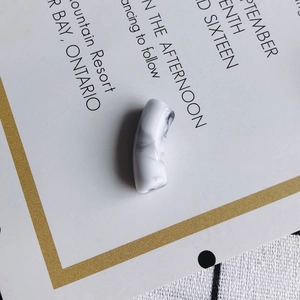 Détail de perle tube courbé en acrylique marbré pour la création de bijoux DIY