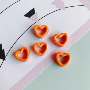 Detailansicht von fünf orangefarbenen Herzperlen für DIY-Schmuck und Bastelprojekte