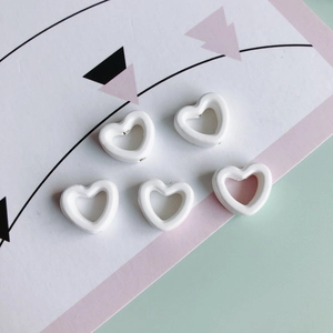 Nahaufnahme von fünf weißen hohlen Herzkeramikperlen für DIY-Schmuck und Ohrringe