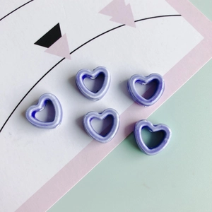 Makroaufnahme von fünf hellvioletten hohlen Herz-Keramikperlen für DIY-Schmuck