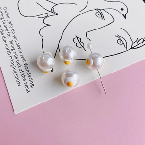 Detailed view of white pearl beads with cute fried egg enamel patterns for DIY jewelry craft
