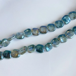 Macro view of iridescent blue-green laser glass beads in irregular square shape