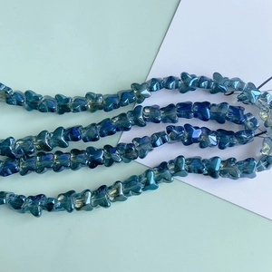 Close-up of iridescent blue gradient glass butterfly beads for DIY jewelry making